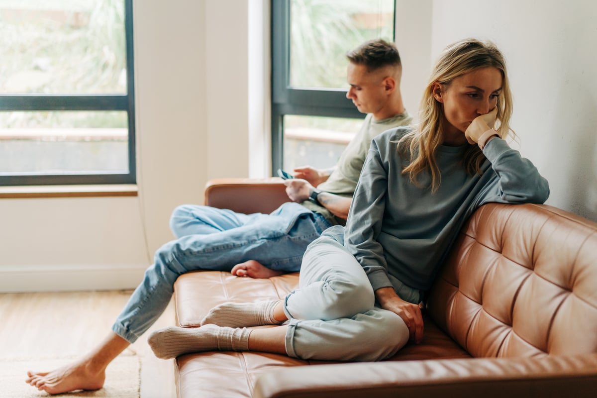 Sad Woman Ignored by Her Husband Using Smartphone on Sofa